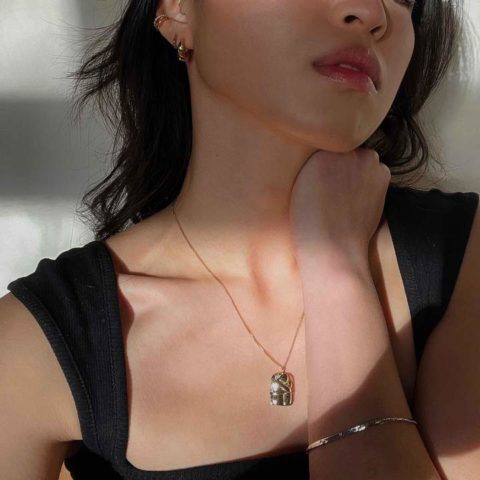 A woman wearing the Embrace Pendant Necklace in Gold