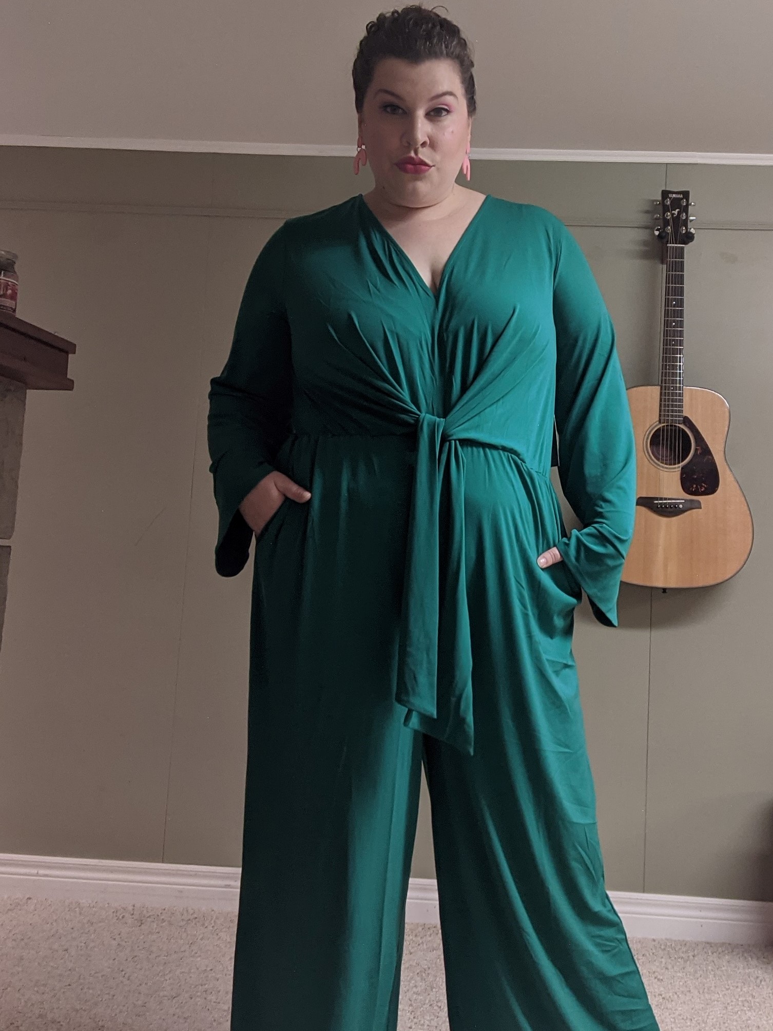 Lora wearing a drapey emerald green jumpsuit with long sleeves.