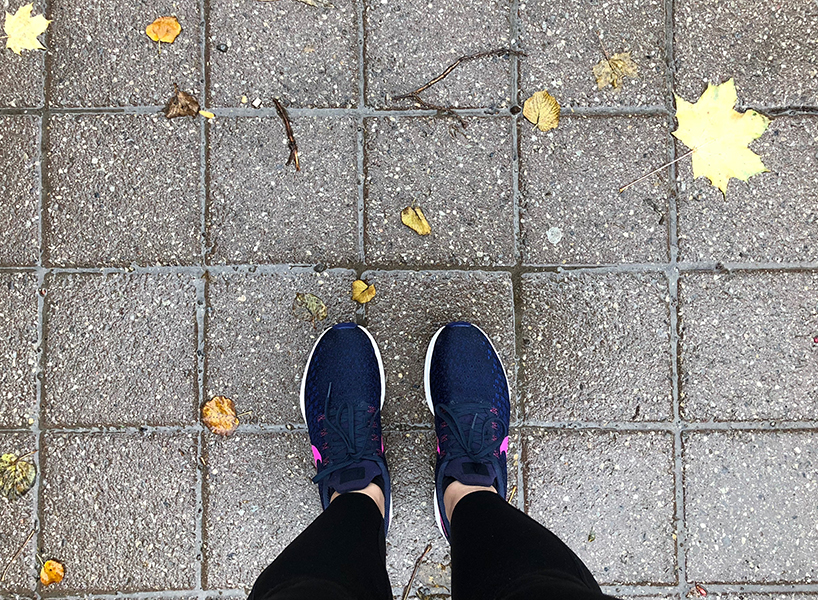 A view looking down at a woman's sneakers standing on pavement