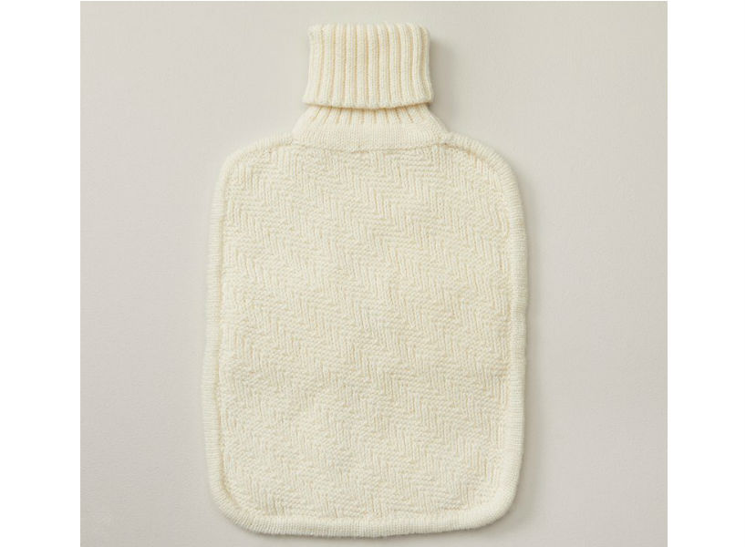 Hot water bottle with a white, knitted cover