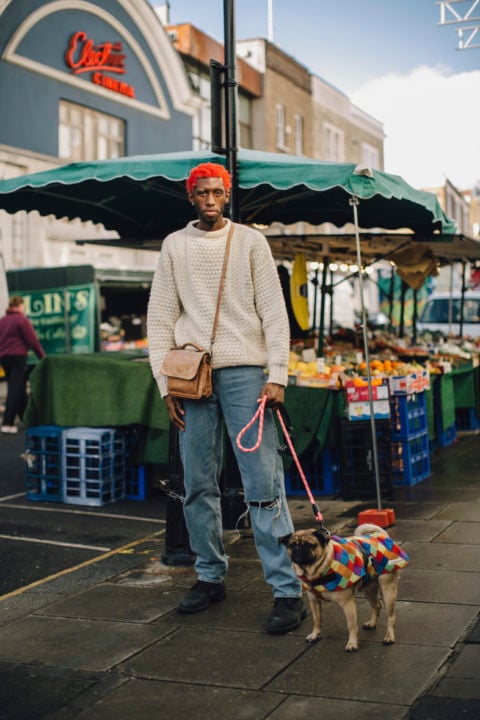man with orange hair beige sweater jeans and dog