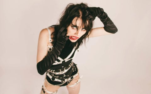 goth woman with gloves and bodysuit and black hair