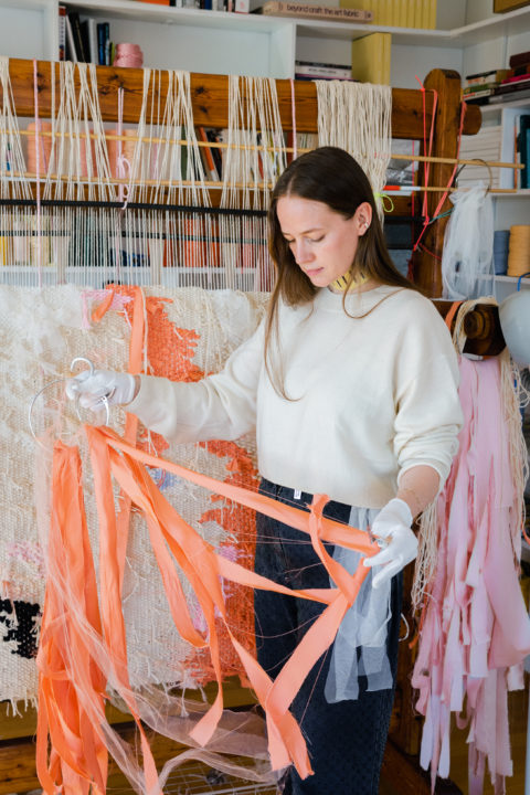 Ann Cathrin November Høibo in an art studio holding a pink fabric