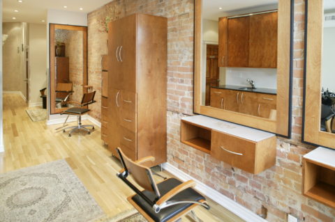 inside jazma hair salon in toronto. the salon is empty with a brick wall and chair facing a mirror