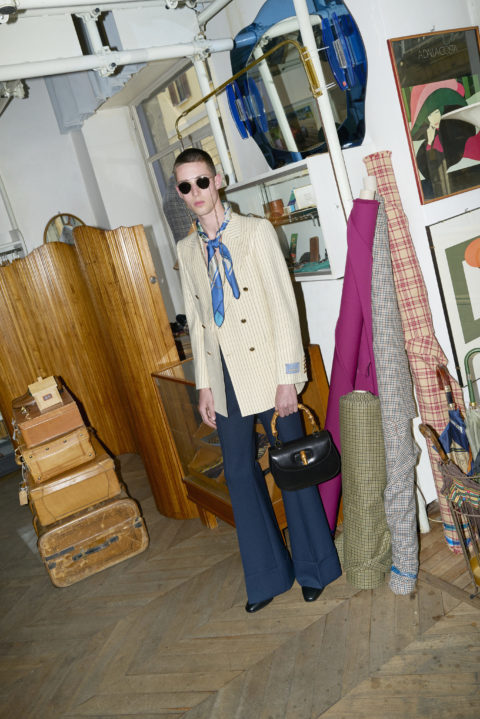 model wears a beige suit jacket,black purse and blue scarf from the gucci: ha ha ha collection