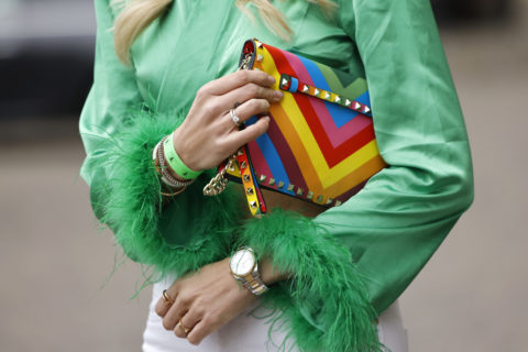 woman in a green shirt holding a rainbow clutch
