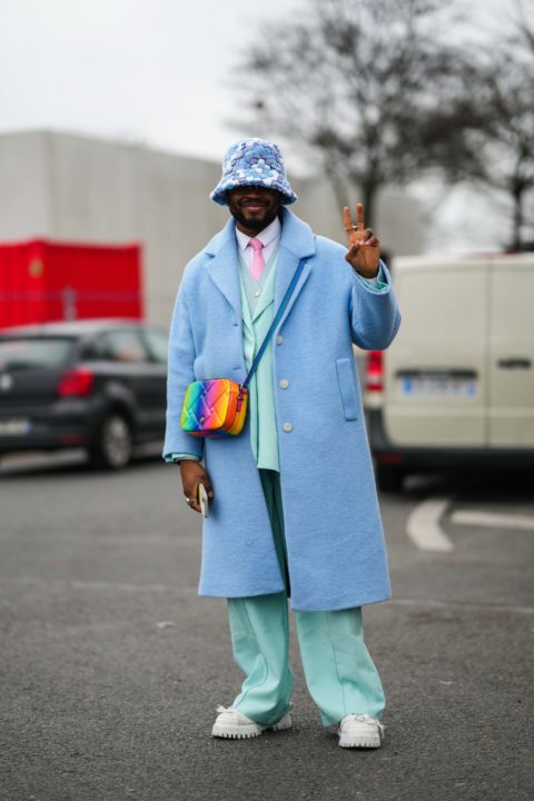 man in blue suit and bucket hat with rainbow purse inspo for what to wear to pride 2022