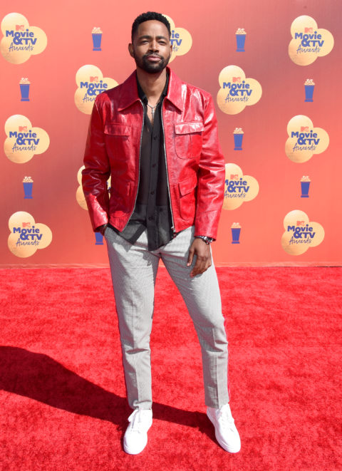 jay ellis attends the 2022 mtv movie & tv awards red carpet in a red leather jacket,black shirt and grey pants