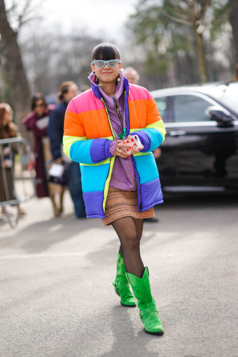 woman in a rainbow puffer with green sunglasses