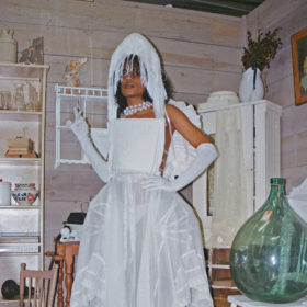 a model wears a gorm white dress and headpiece with white gloves