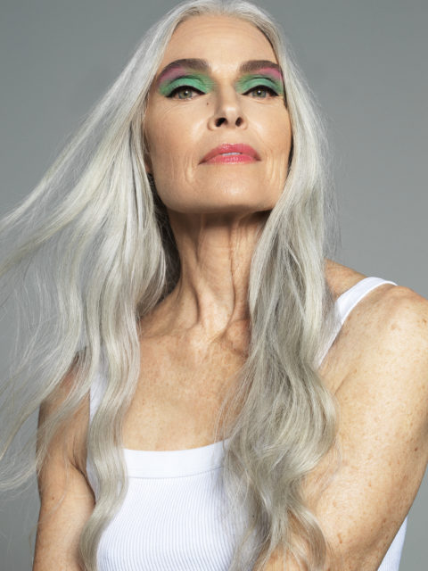 An older model wearing a colourful eye makeup look from Haus Labs