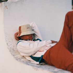 Adidem Asterisks* summer campaign image model in bucket hat sweater and pants lying down