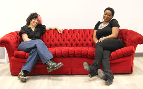 Two people sitting side by side on a red sofa