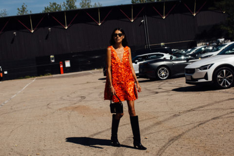 attendee at copenhagen fashion week spring 2023 wearing an orange dress and black boots