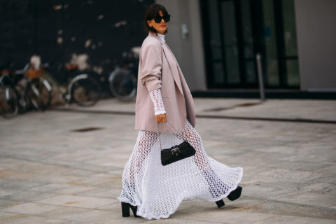 a street style photo of a person wearing a maxi skirt in a white semi-sheer fabric