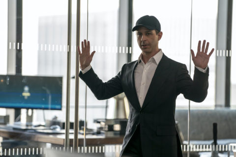 a still from the tv show succession of kendall roy wearing a white dress shirt, dark blazer and black baseball hat