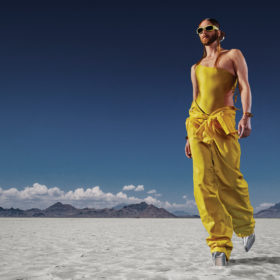 Myles Sexton poses in a yellow outfit in a desert