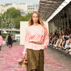  A model walking with a pink top and tweed skirt, holding a basket of flowers at Chanel couture 2023 show