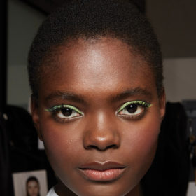 Model backstage wearing green pastel eyeliner